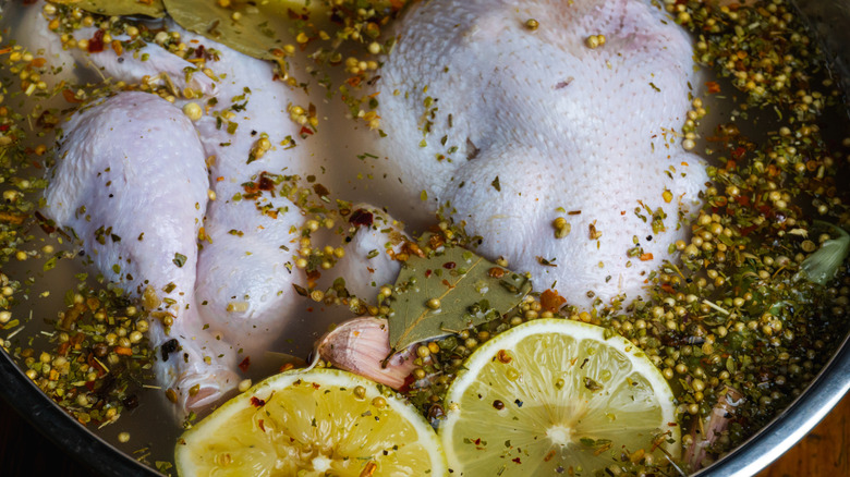 A chicken in a pot being poached with lemon and spices