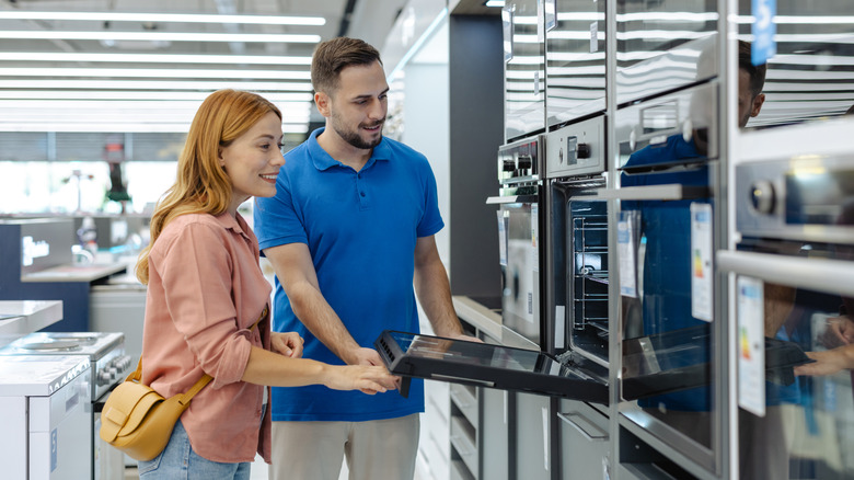 Two people looking at an in-wall oven in a retail store