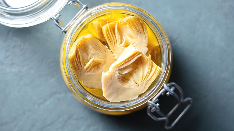 Opened glass jar of artichoke hearts