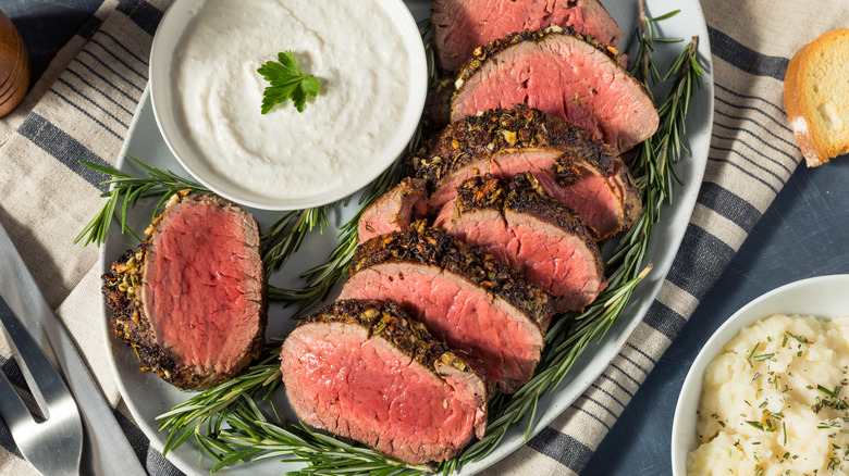 A medium rare beef tenderloin served with sauce