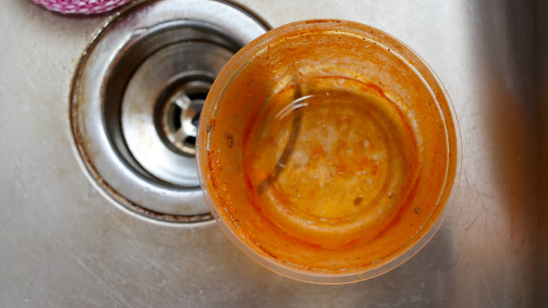 stained plastic food storage container in a kitchen sink