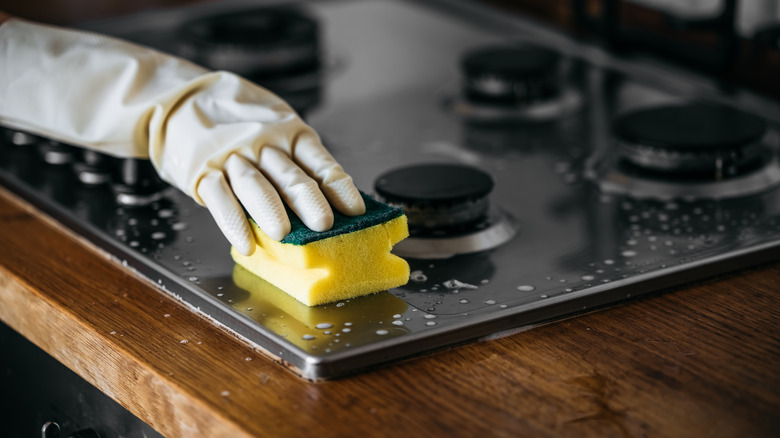 An individual cleaning a stove.