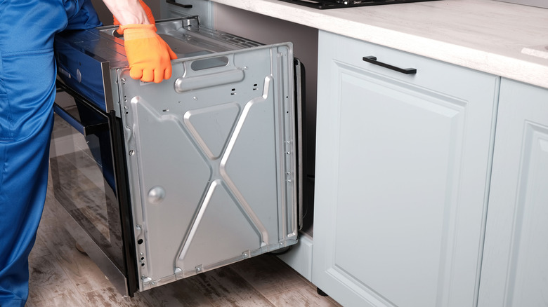 Person moving an oven out of a kitchen