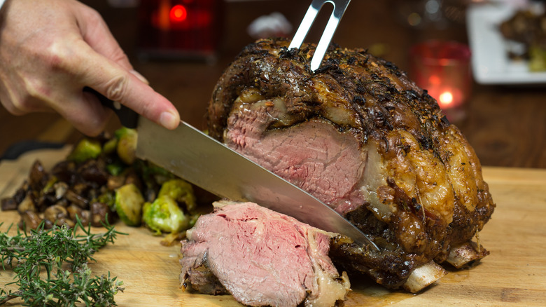 Person cutting a prime rib