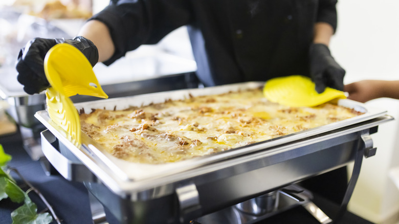 Person setting up hotel pan of food