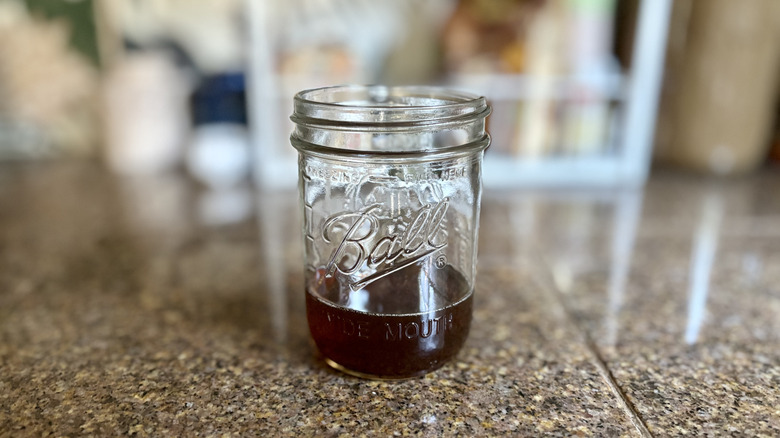 An open jar of bacon grease cooling on a counter