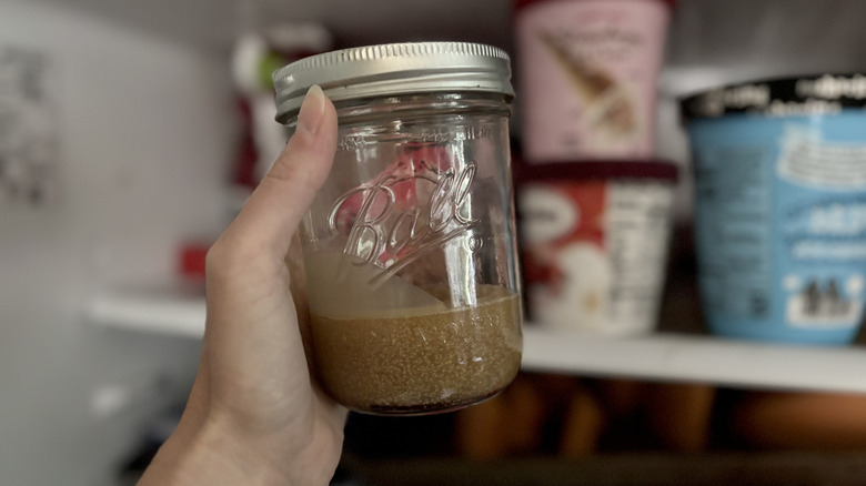 Someone taking a jar of frozen bacon grease out of the freezer