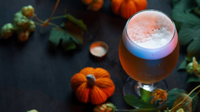 glass of beer on table with small crochet pumpkins and leaves