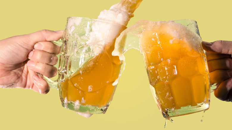 two beers cheers and slosh out of their glasses