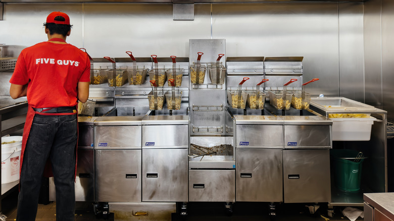 A Five Guys employee is seen working in a kitchen.