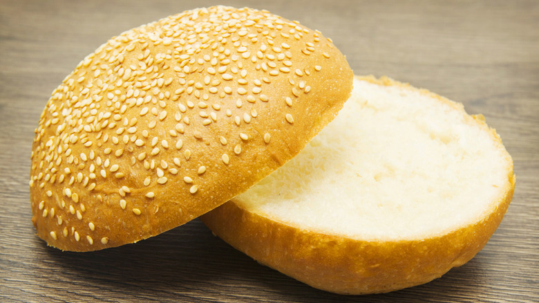 A sesame seed bun in closeup on a wooden table.