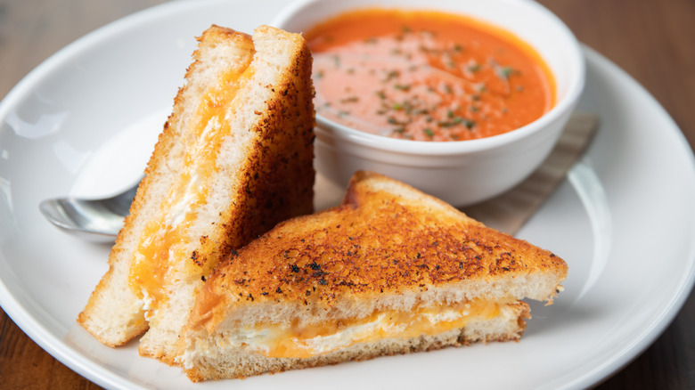 A golden brown grilled cheese sandwich with a small bisque on the side brightens up any morning