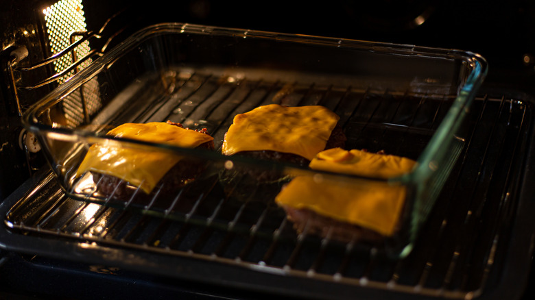 Burgers with cheese cooking in a glass casserole dish in the oven