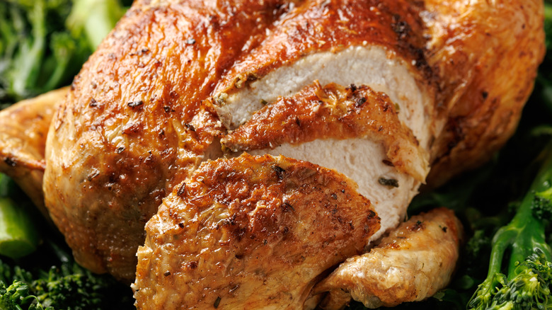 A close-up of a roasted chicken with sliced-up parts revealing tender meat