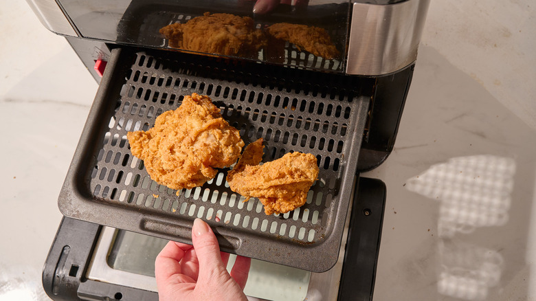 Adding chicken pieces to an air fryer