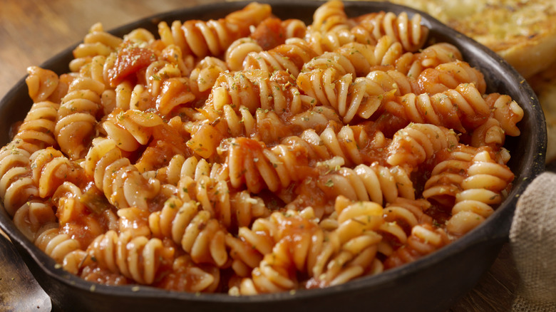 pasta in a large saute pan is garnished with herbs