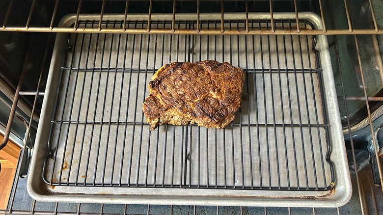 Ribeye teak on a baking sheet lined with a cooling rack in the oven