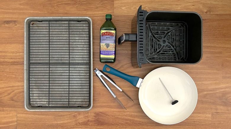 Baking sheet, air fryer basket, skillet, thermometer, tongs, cooling rack, and container of grapeseed oil