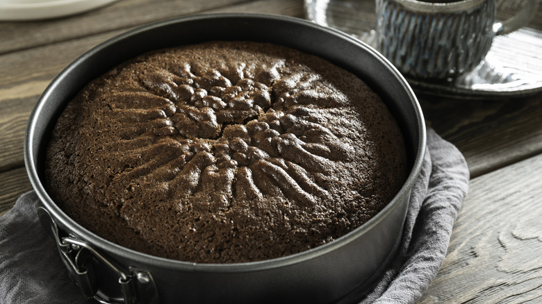 A dark brown cake in a stainless pan.