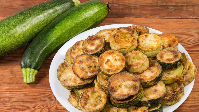 fried zucchini slices next to fresh zucchini