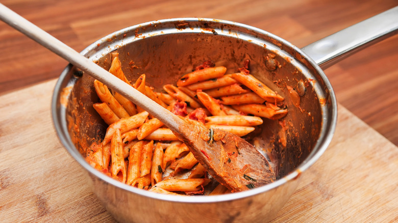 leftover penne in sauce in a steel cooking pot