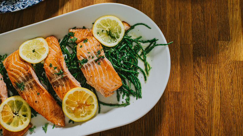 Browned salmon filets on top of greens with lemons