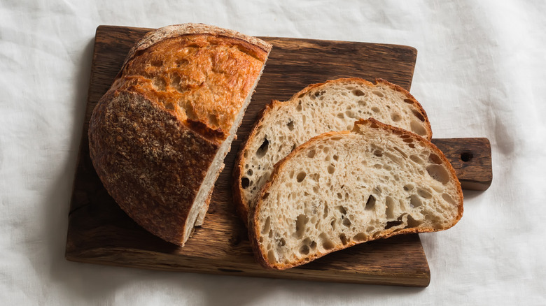 Sourdough homemade tartine bread on a wooden cutting board on a light background, top view