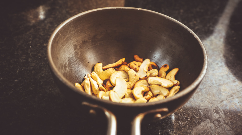 A handful of roasted cashews in a pan on a countertop.