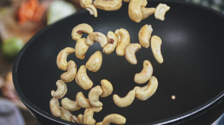 Wok roasting cashews and flipping them in the air.