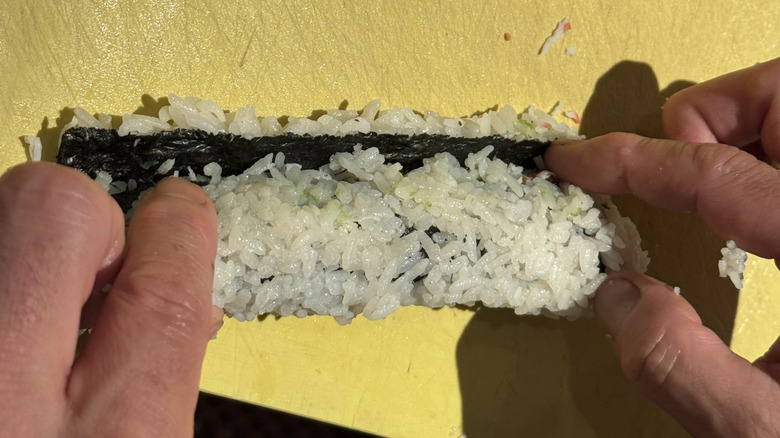 Hands rolling a sushi roll