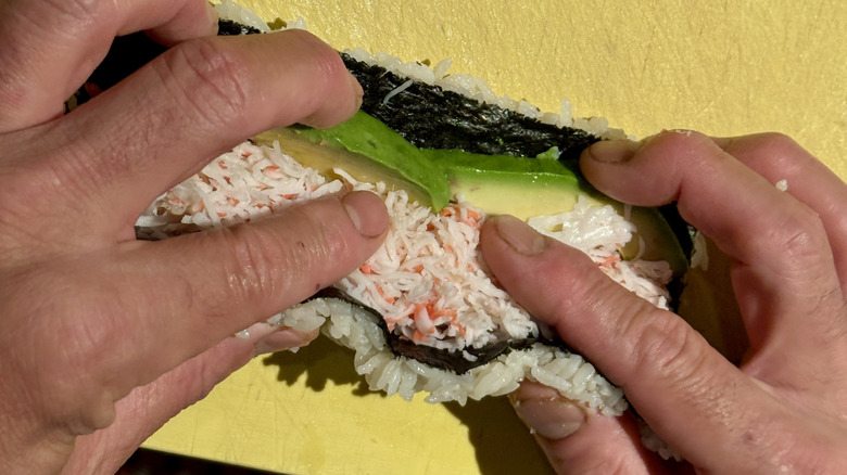 Hands rolling a California roll