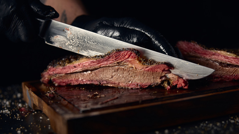 Gloved hands cut brisket
