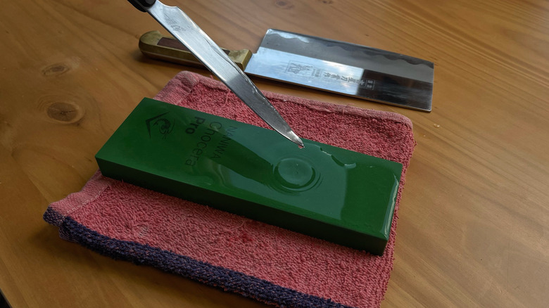 A blade dripping water onto a whetstone