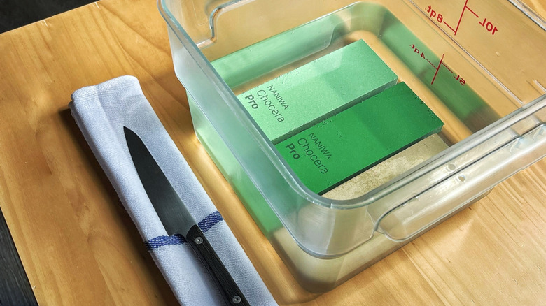Three whetstones soaking in a Cambro of water