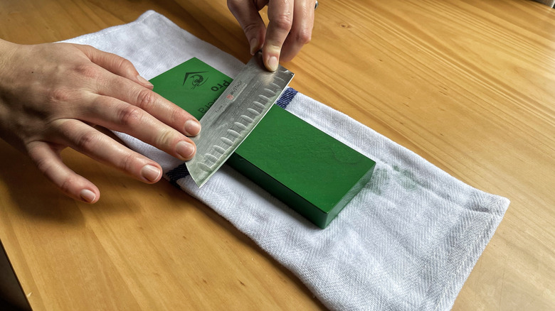 A knife positioned at a 20 degree angle on top of a whetstone
