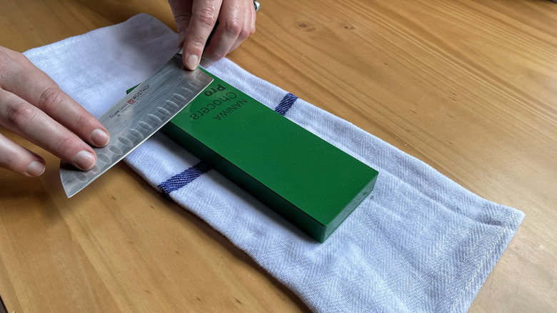 The back end of the knife is placed at the bottom of the stone to begin the stroke