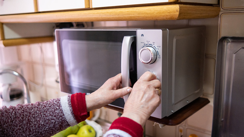 someone twisting a dial on a microwave