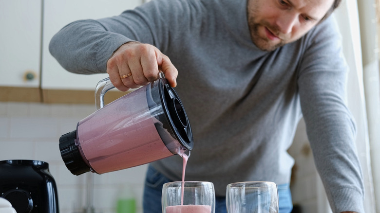 A man pouring milkshakes from a blender