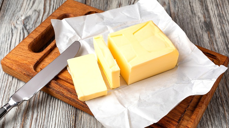 Block of opened, partially-sliced butter on a wooden cutting board