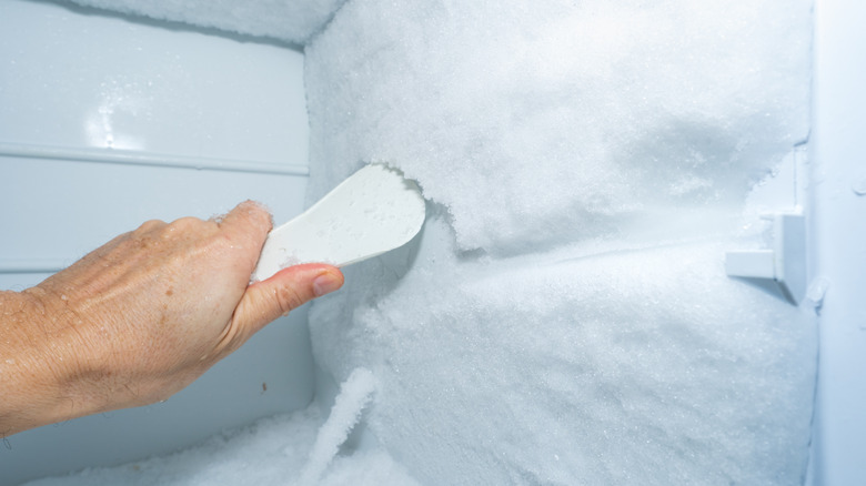 Using a plastic scrapper to remove ice build up in a freezer