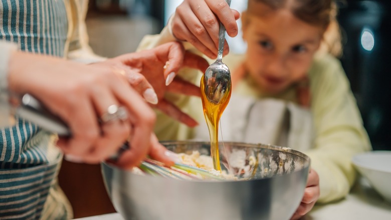 Adding honey to a mixing bowl