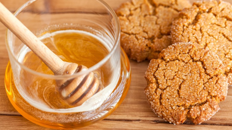A cup of honey and some ginger cookies