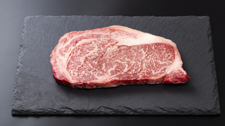 A wagyu steak on a black cutting board.