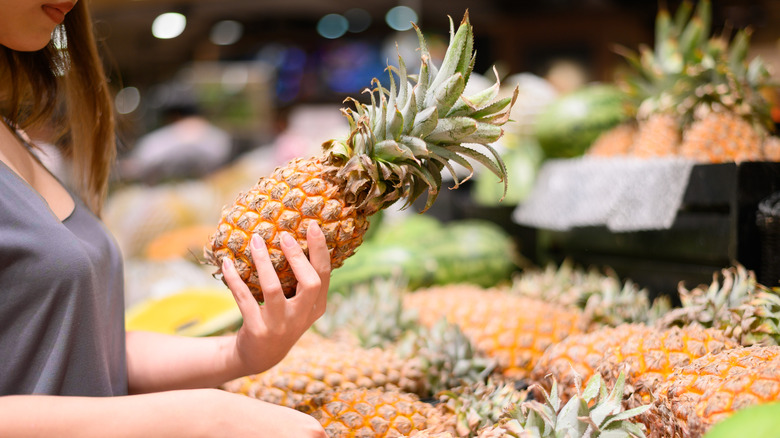 person holding a pineapple at the grocery store