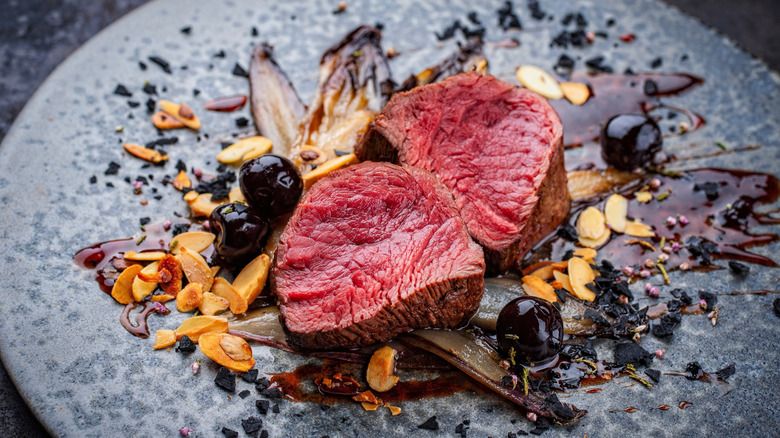 rare dry-aged steak on a plate with garnishes