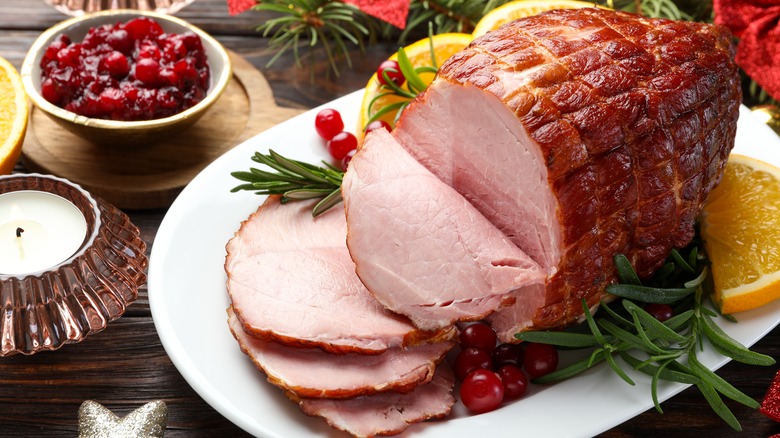 Baked glazed ham on a plate with herbs