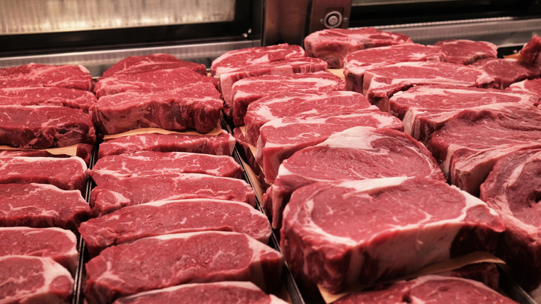 Steaks are displayed at a grocery butcher counter.