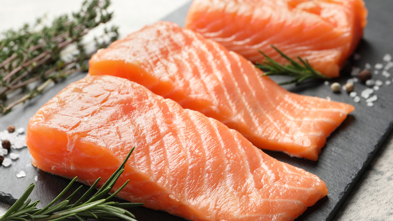 Three filets of fresh raw salmon on a black slate