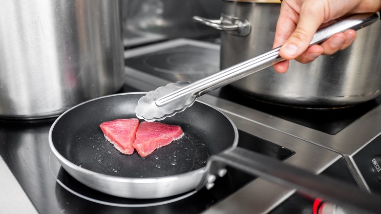 Person searing two tuna steaks