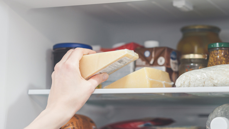 Someone taking cheese out of the fridge